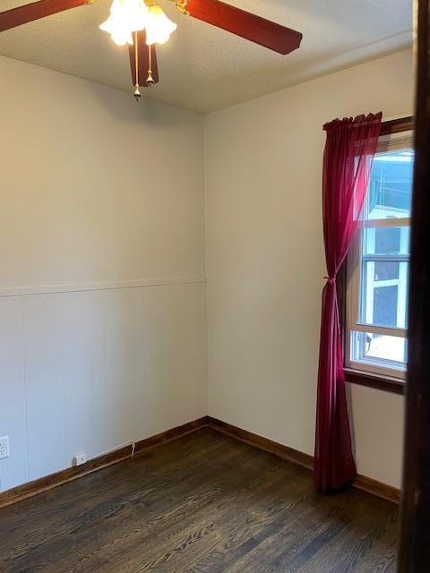 empty room featuring baseboards, a ceiling fan, and wood finished floors