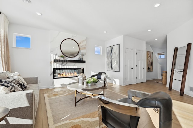 living area featuring light wood finished floors, a fireplace, and recessed lighting