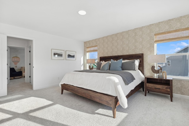 bedroom featuring light colored carpet, baseboards, and wallpapered walls