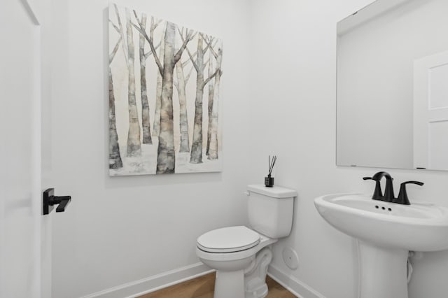 bathroom with a sink, wood finished floors, toilet, and baseboards