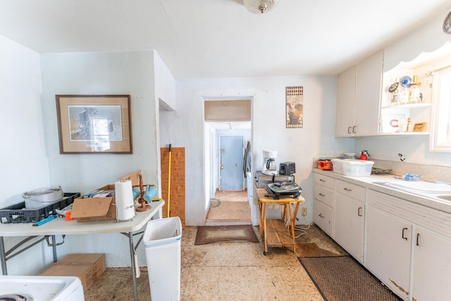 kitchen featuring light countertops, a sink, and white cabinetry