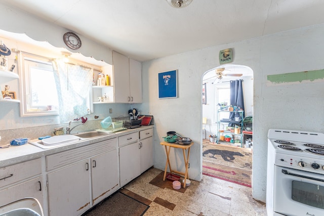 kitchen featuring white range with electric stovetop, arched walkways, white cabinets, light countertops, and open shelves