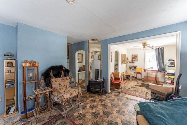 living area with arched walkways and a ceiling fan