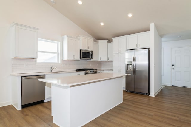 kitchen with a sink, a center island, white cabinetry, appliances with stainless steel finishes, and light countertops