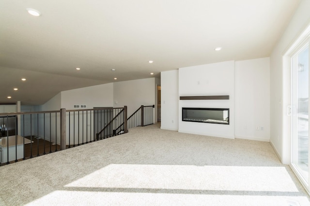 living area with a glass covered fireplace, recessed lighting, carpet, and visible vents