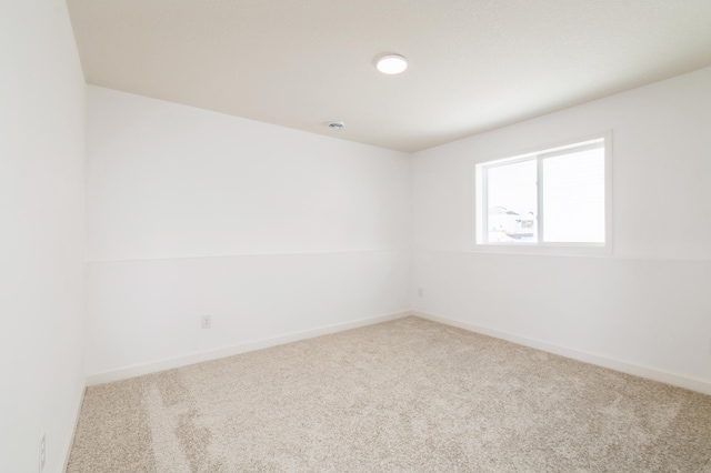 carpeted empty room featuring baseboards