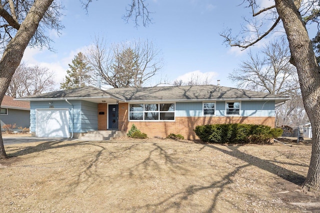 single story home with brick siding, an attached garage, and driveway