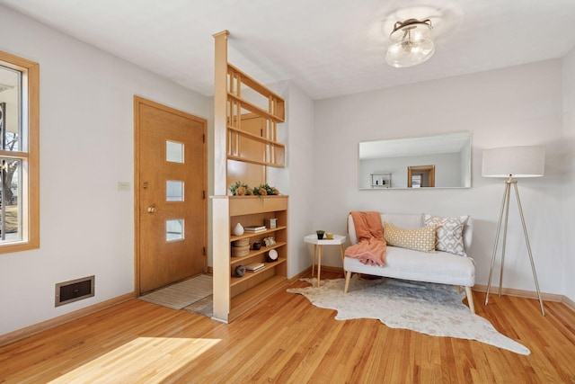 living area with visible vents, baseboards, and wood finished floors