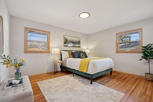 bedroom featuring baseboards, multiple windows, and wood finished floors