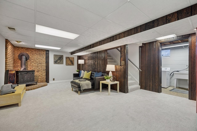 living room with visible vents, a wood stove, carpet floors, a paneled ceiling, and stairs