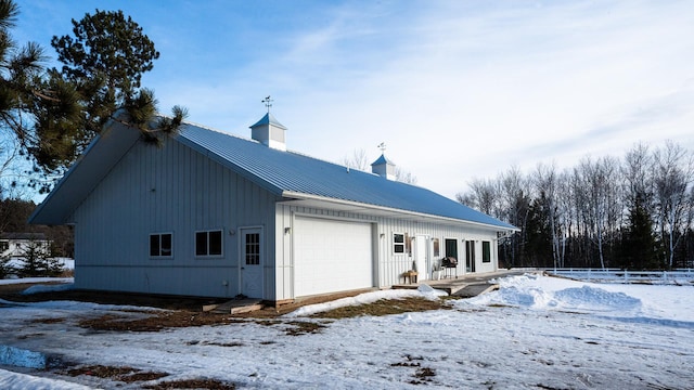 view of front facade featuring an attached garage, a chimney, fence, and metal roof