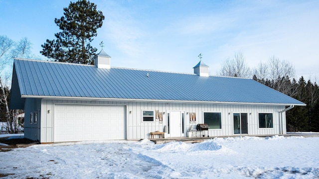 snow covered back of property with a chimney, metal roof, and board and batten siding