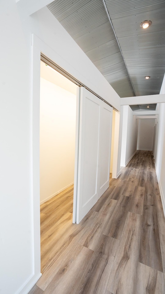 corridor with light wood-style floors, baseboards, and recessed lighting