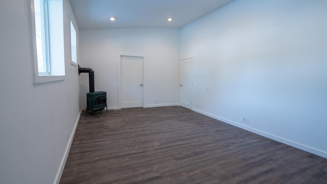 spare room featuring dark wood-style floors, recessed lighting, a wood stove, and baseboards