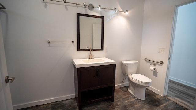 half bathroom featuring toilet, baseboards, and vanity