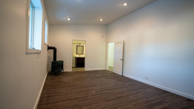 interior space featuring recessed lighting, a wood stove, dark wood finished floors, and baseboards