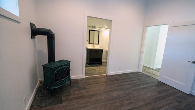 bedroom featuring dark wood-type flooring, a wood stove, and baseboards