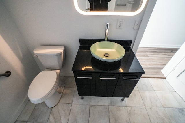 bathroom featuring baseboards, vanity, and toilet