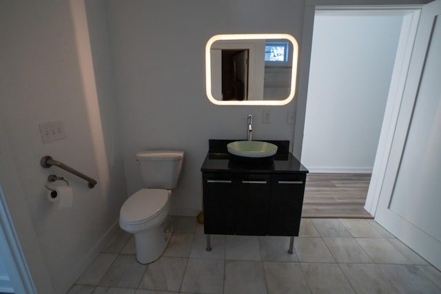 bathroom featuring toilet, baseboards, and vanity