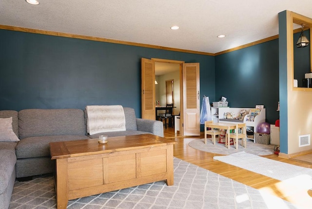 living room with recessed lighting, visible vents, ornamental molding, wood finished floors, and baseboards