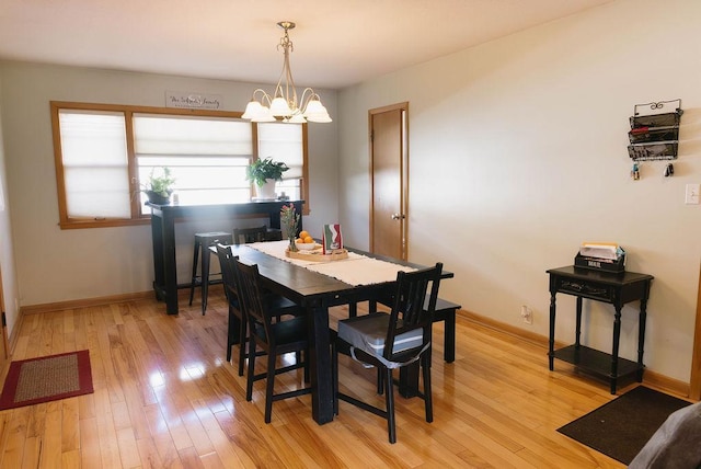 dining space featuring light wood-style flooring, baseboards, and an inviting chandelier