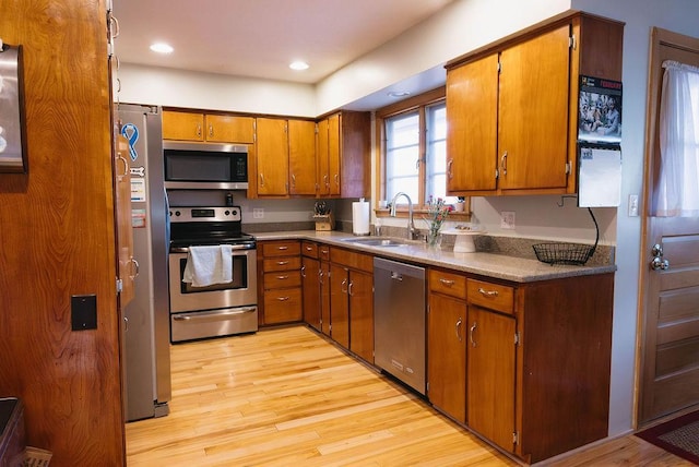 kitchen featuring light wood-style flooring, recessed lighting, a sink, appliances with stainless steel finishes, and brown cabinetry