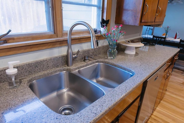 room details with light stone counters, brown cabinetry, and a sink