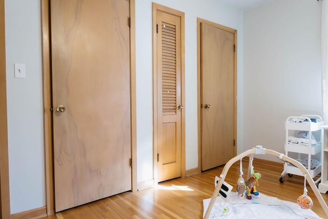 interior space with light wood-style floors, baseboards, and two closets