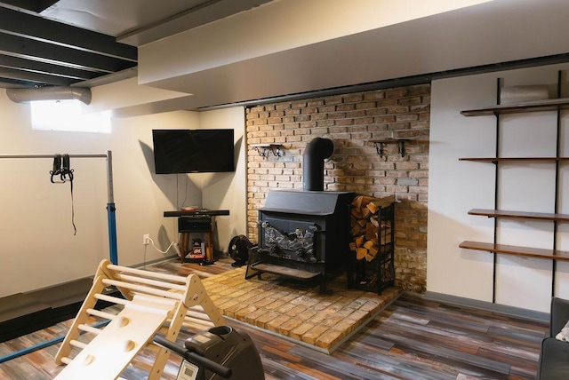 interior space featuring wood finished floors, a wood stove, and baseboards