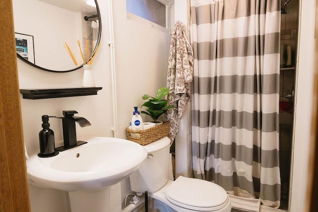 bathroom with curtained shower, a sink, and toilet