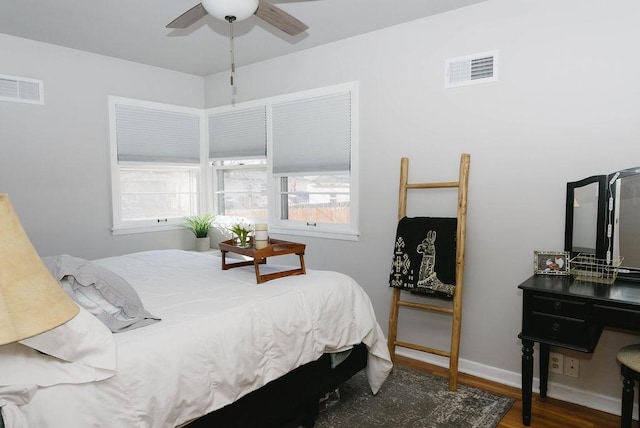 bedroom featuring a ceiling fan, baseboards, visible vents, and wood finished floors