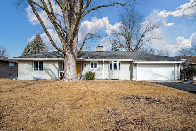 ranch-style home with a garage, driveway, a front lawn, and a chimney