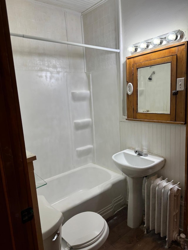 bathroom with radiator, toilet, wood finished floors, and bathing tub / shower combination