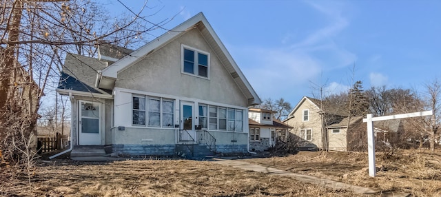 view of front facade featuring entry steps, roof with shingles, and stucco siding