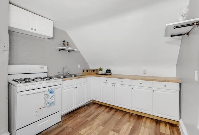 kitchen featuring lofted ceiling, white gas range oven, open shelves, and a sink