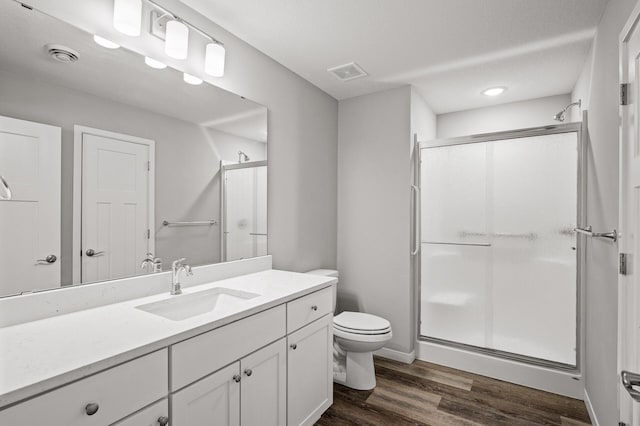 full bath with vanity, wood finished floors, visible vents, and a stall shower