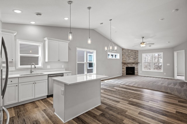 kitchen featuring a sink, a stone fireplace, white cabinets, light countertops, and dishwasher