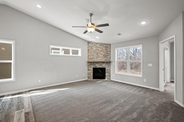 unfurnished living room with a ceiling fan, recessed lighting, a stone fireplace, baseboards, and vaulted ceiling