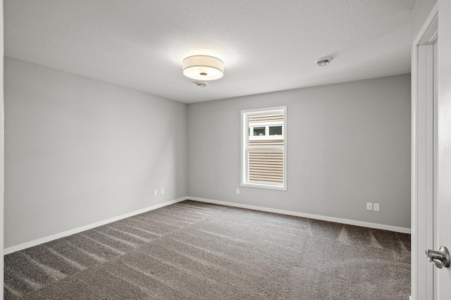 spare room featuring a textured ceiling, baseboards, and carpet