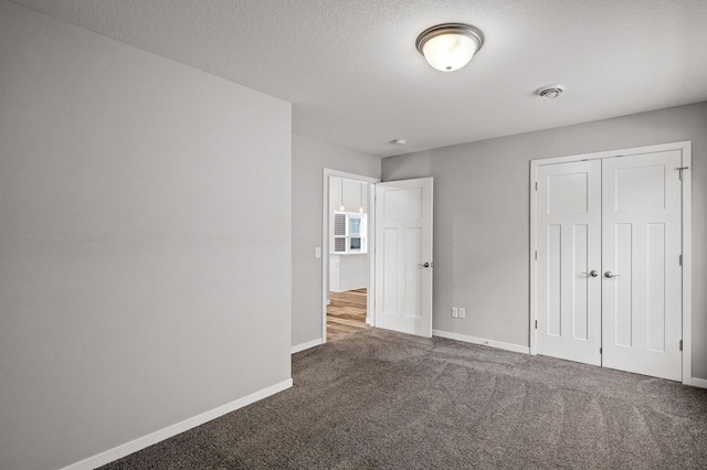 unfurnished bedroom featuring carpet flooring, baseboards, a closet, and a textured ceiling