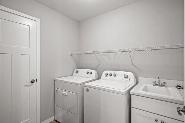 washroom with cabinet space, separate washer and dryer, and a sink