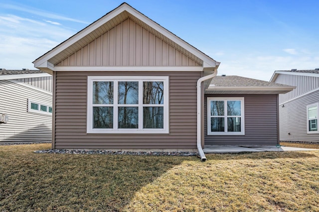 view of home's exterior with a patio area, board and batten siding, a shingled roof, and a yard