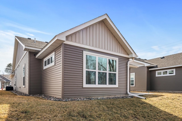 rear view of house featuring a lawn, board and batten siding, and roof with shingles