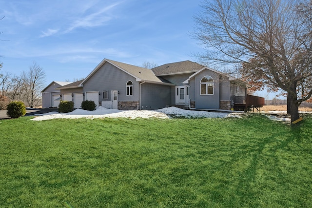 back of property with an attached garage, stone siding, and a lawn