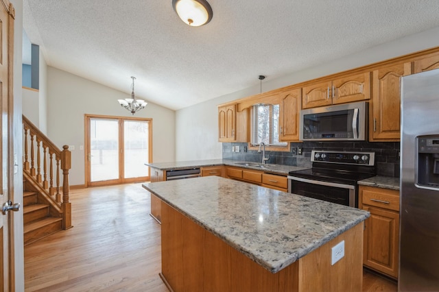 kitchen featuring appliances with stainless steel finishes, a wealth of natural light, lofted ceiling, and a peninsula