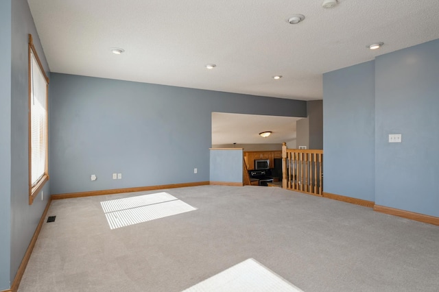 unfurnished living room with carpet, visible vents, baseboards, and recessed lighting