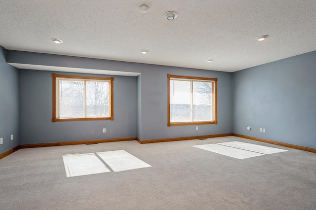 unfurnished room with a textured ceiling, baseboards, and carpet flooring