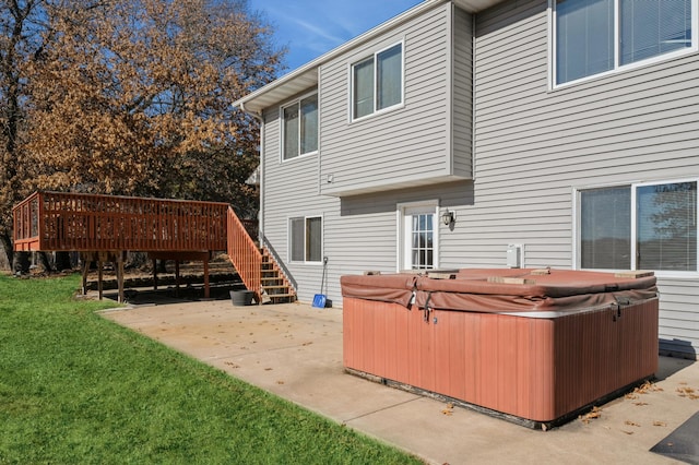 exterior space featuring a hot tub, stairway, a yard, a wooden deck, and a patio area