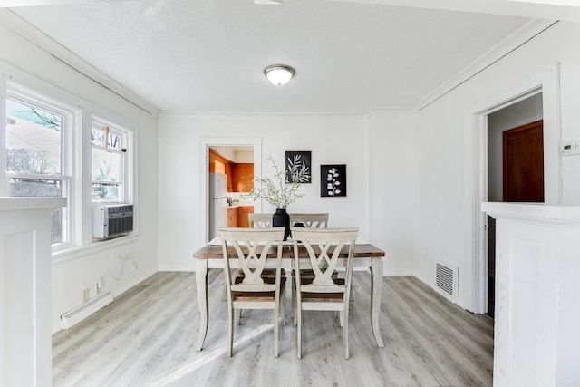 dining room featuring light wood-type flooring, cooling unit, visible vents, and crown molding