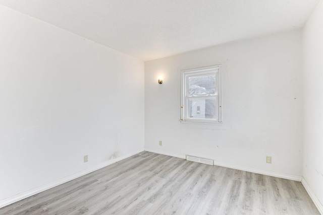 spare room featuring baseboards, a textured ceiling, visible vents, and wood finished floors